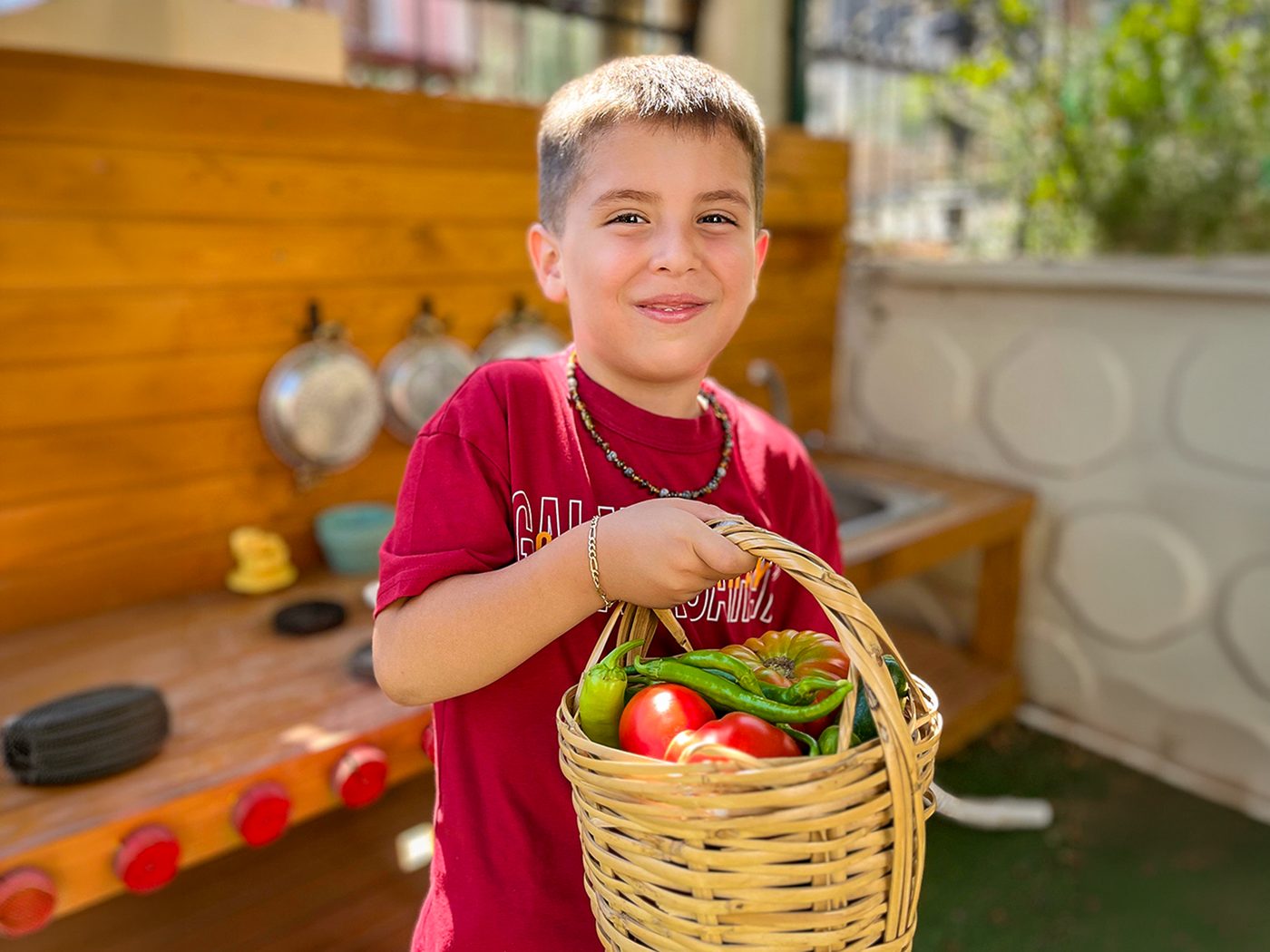 Bahçe mutfağında sebze sepetini gösteren çocuk